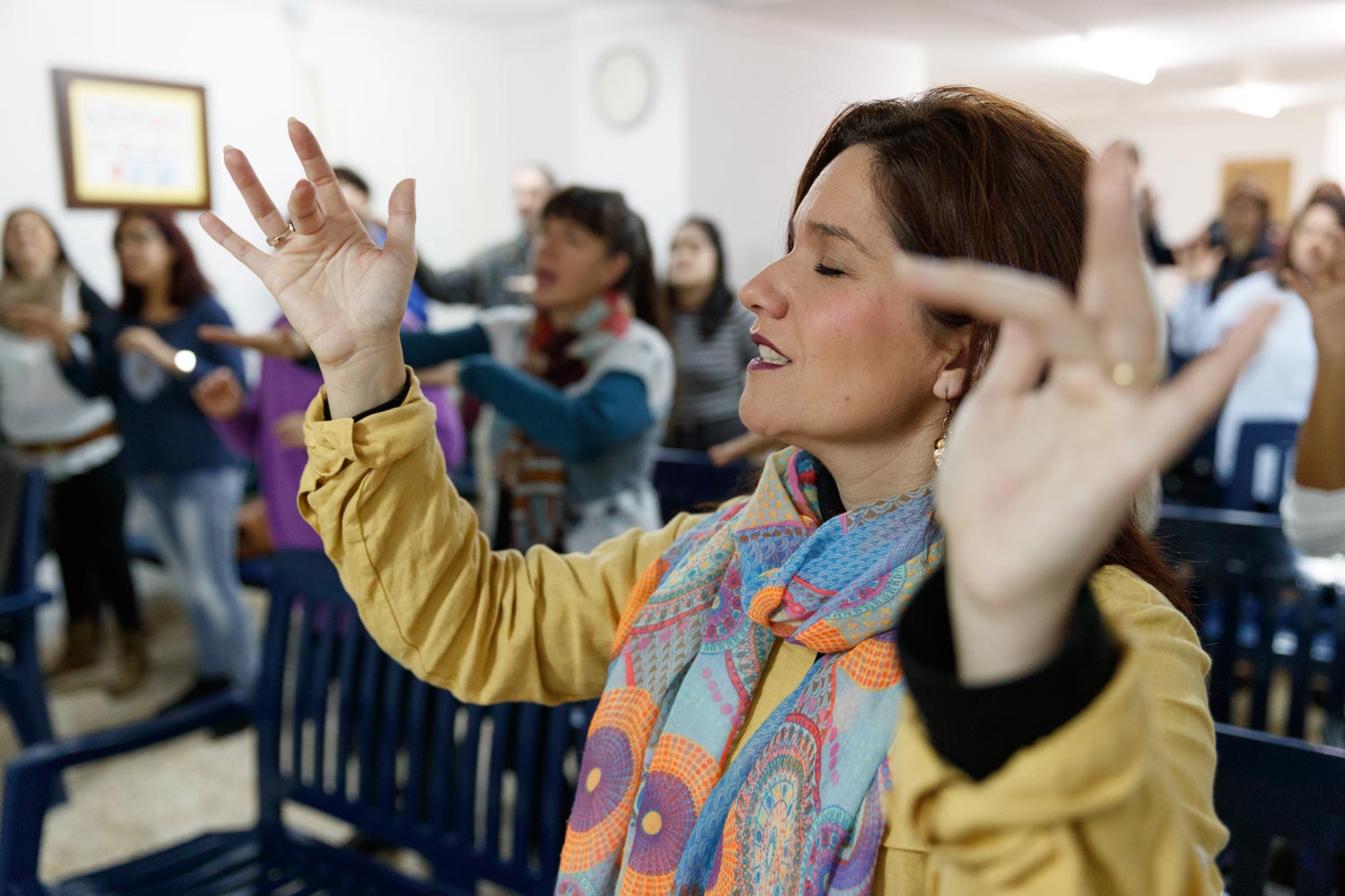 Woman and congregation worshipping with hands raised